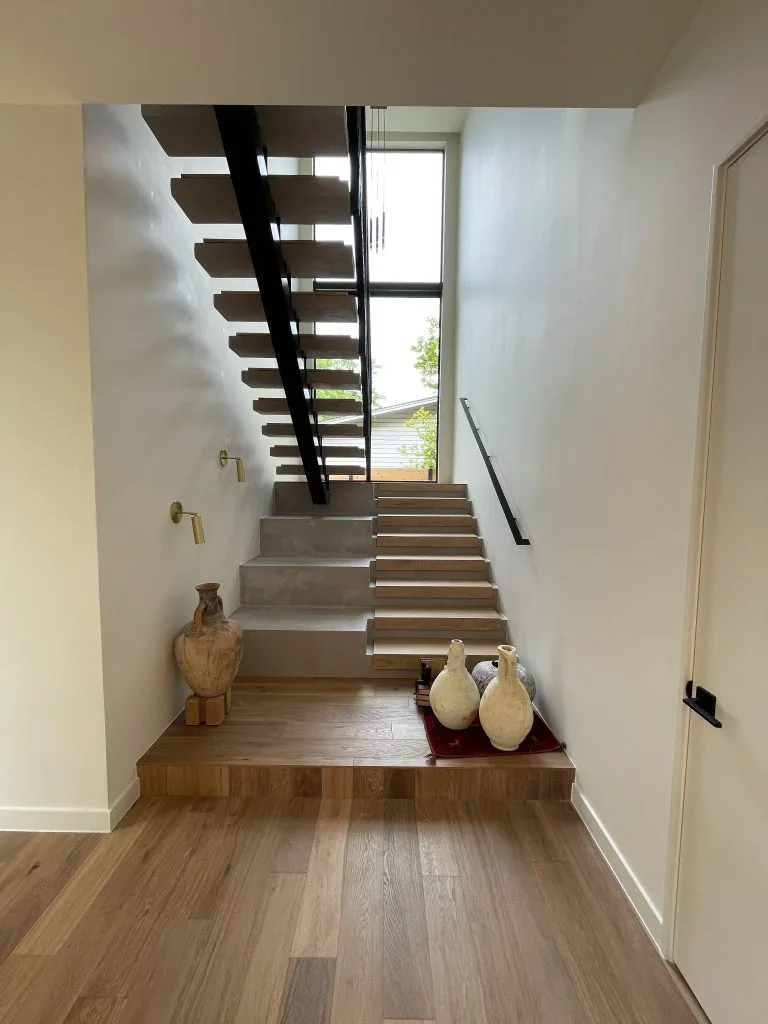 Seamless microcement feature wall and stair treads in a modern entryway