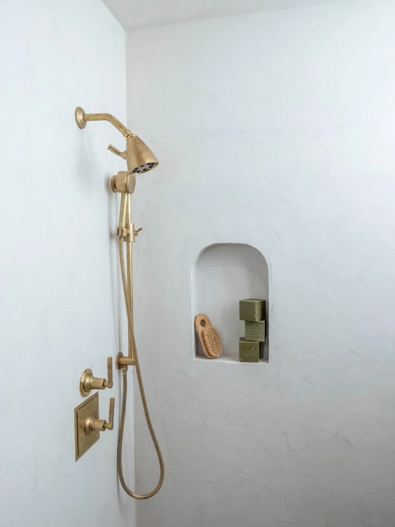 Waterproof microcement shower wall with brass fixtures and built-in niche
